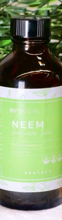 A bottle of pure neem carrier oil with fresh leaves in the background.