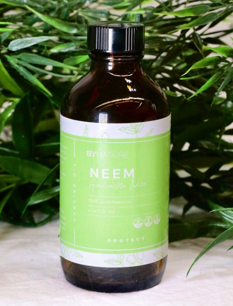 A bottle of pure neem carrier oil with fresh leaves in the background.