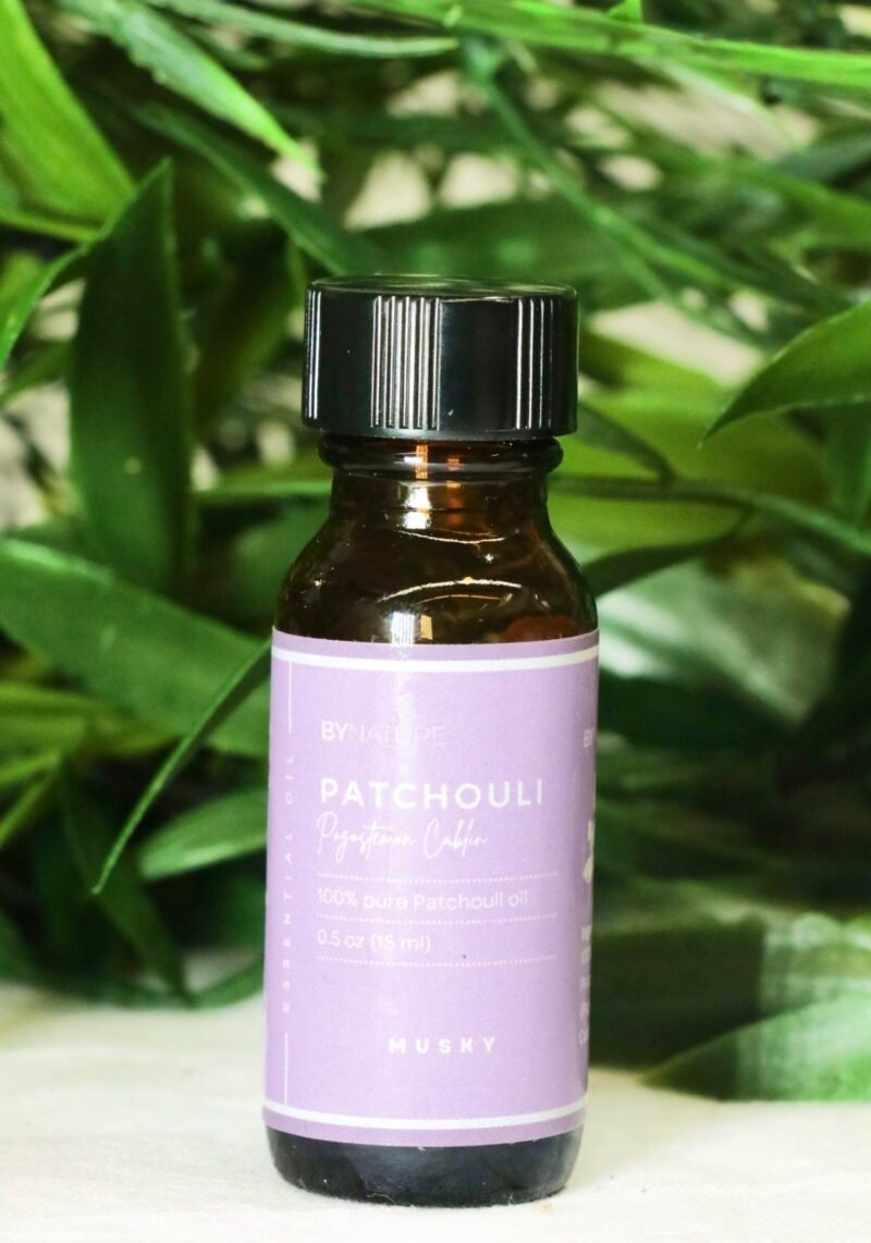 A bottle of pure patchouli essential oil with fresh leaves in the background.