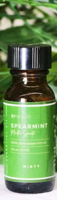 A bottle of pure spearmint essential oil with fresh leaves in the background.