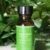 A bottle of pure spearmint essential oil with fresh leaves in the background.
