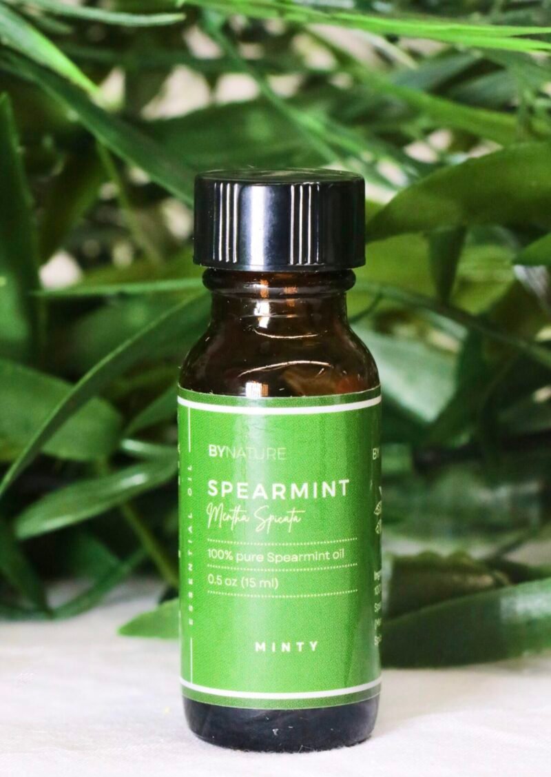 A bottle of pure spearmint essential oil with fresh leaves in the background.