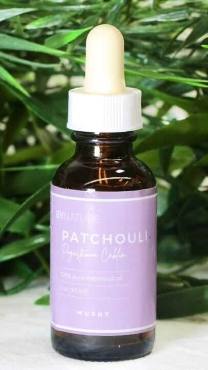 A bottle of pure patchouli essential oil with fresh leaves in the background.