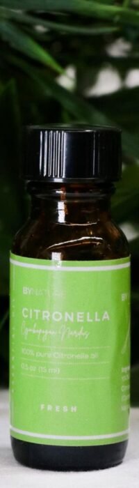 A bottle of pure citronella essential oil with fresh leaves in the background.