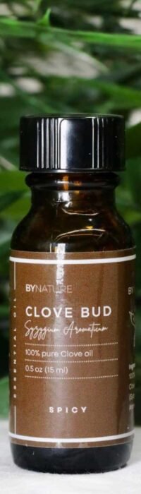 A bottle of pure clove bud essential oil with fresh leaves in the background.
