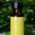 A bottle of pure lemon essential oil with fresh leaves in the background.